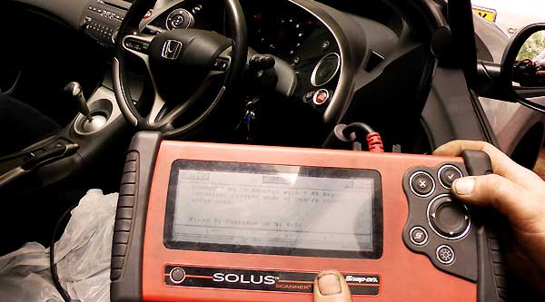 close up of computer fault finding diagnosis equipment with screen showing the device connecting to the vehicles on board computer to diagnose any faults