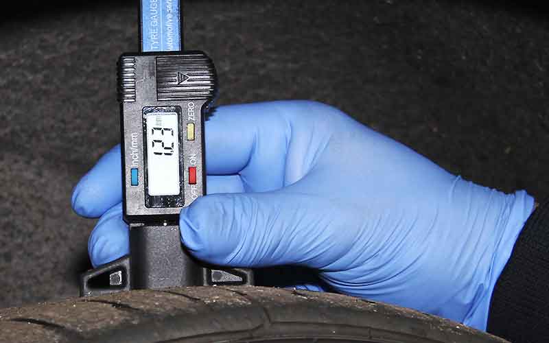 close up of a tyre with a digital tread depth measure displaying in milimeters 1.23 which makes this tyre illegal