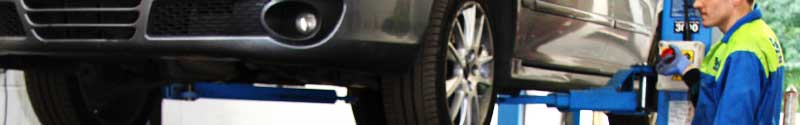 black shiny mercedes car being lifted on a ramp by a mechanic about to repair the vehicles clutch