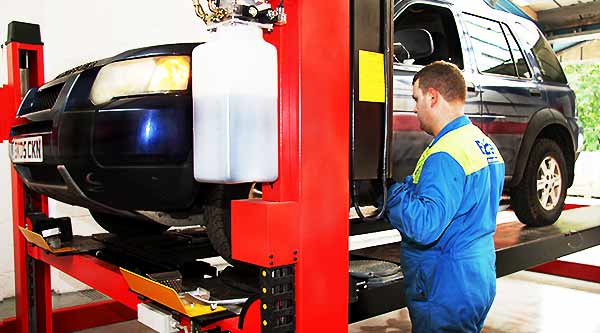 close up of dave brown mot testing a land rover stood at the front passenger corner operating a ramp upwards