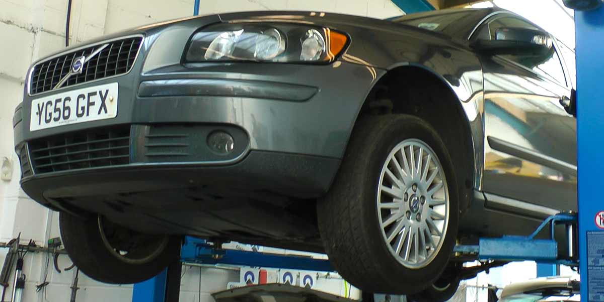 older volvo d5 high in the air on a ramp with a mechanic inspecing for potential and existing issues