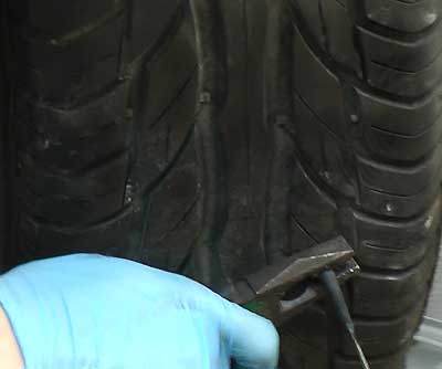 close up of a tyre with a puncture plug patch being held in place by the repairer