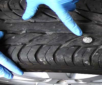 tyre with a nail sticking out and an excel tyre expert pointing straight at it