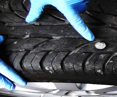 tyre with a nail sticking out and an excel tyre expert pointing straight at it